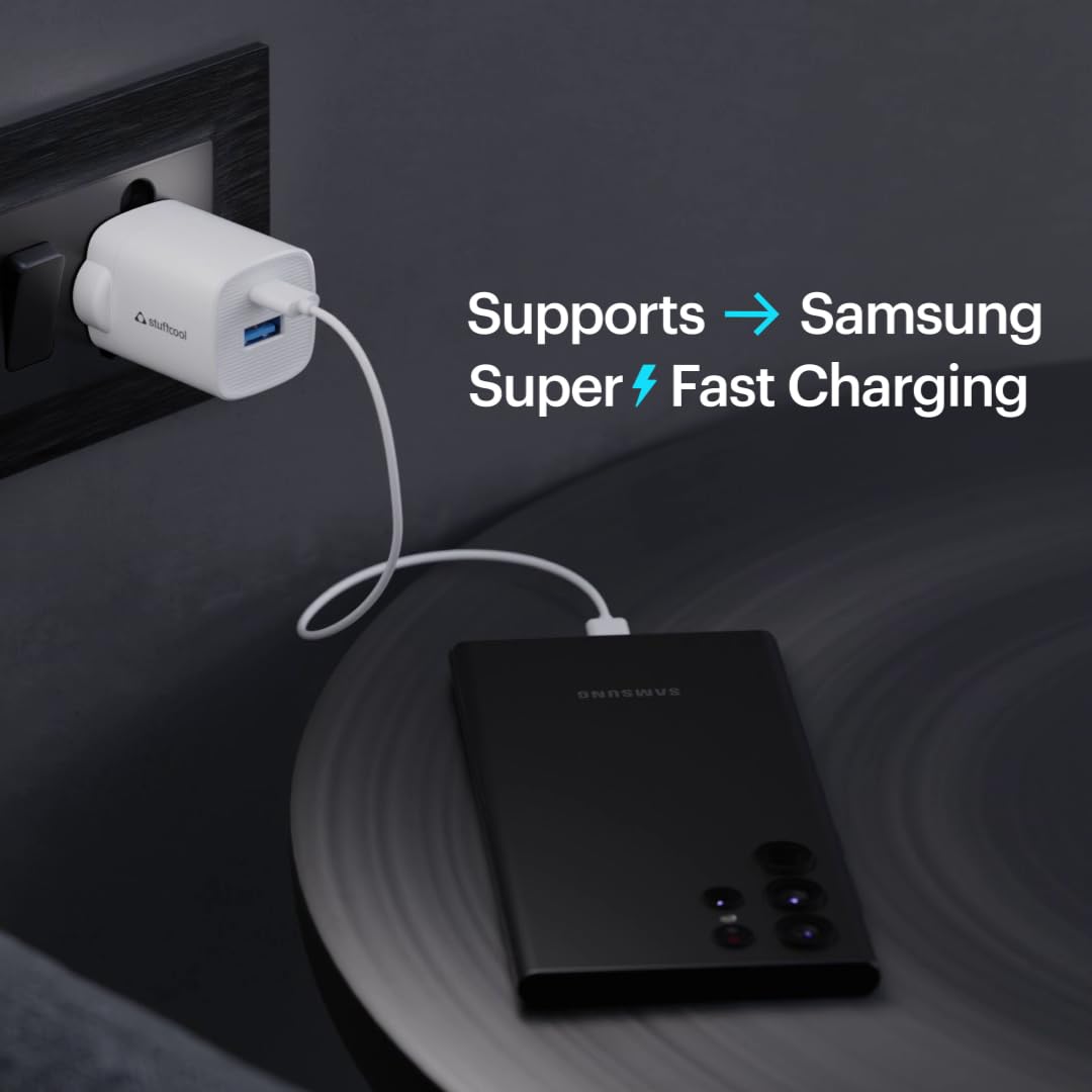 A black portable power bank with a white cable plugged into a white USB charger, shown on a dark surface with text that says it supports Samsung super fast charging.