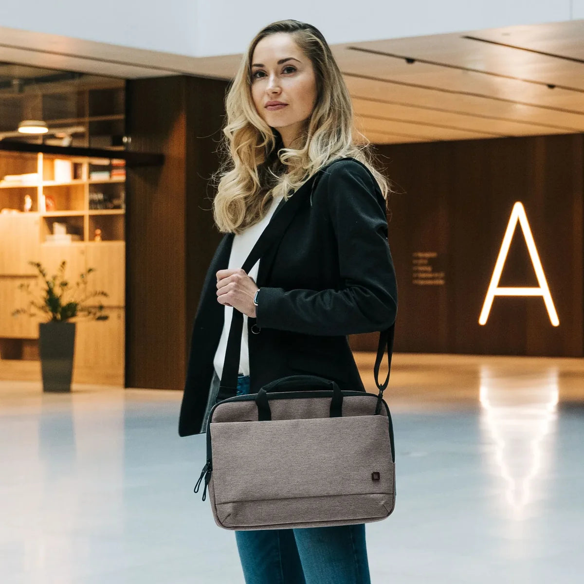 Woman holding a gray briefcase in an indoor setting with a modern design.