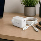 White charging adapter with cable on a wooden desk with a plant in the background